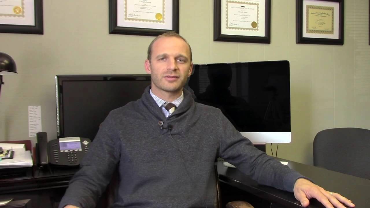 Asheville car accident lawyer Lakota Denton wearing grey cowl-neck sweater in Asheville office.