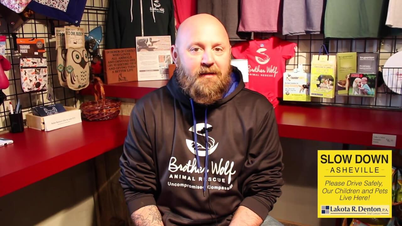 Asheville Brother Wolf Animal Rescue Host Wearing Black Sweater with White Lettering