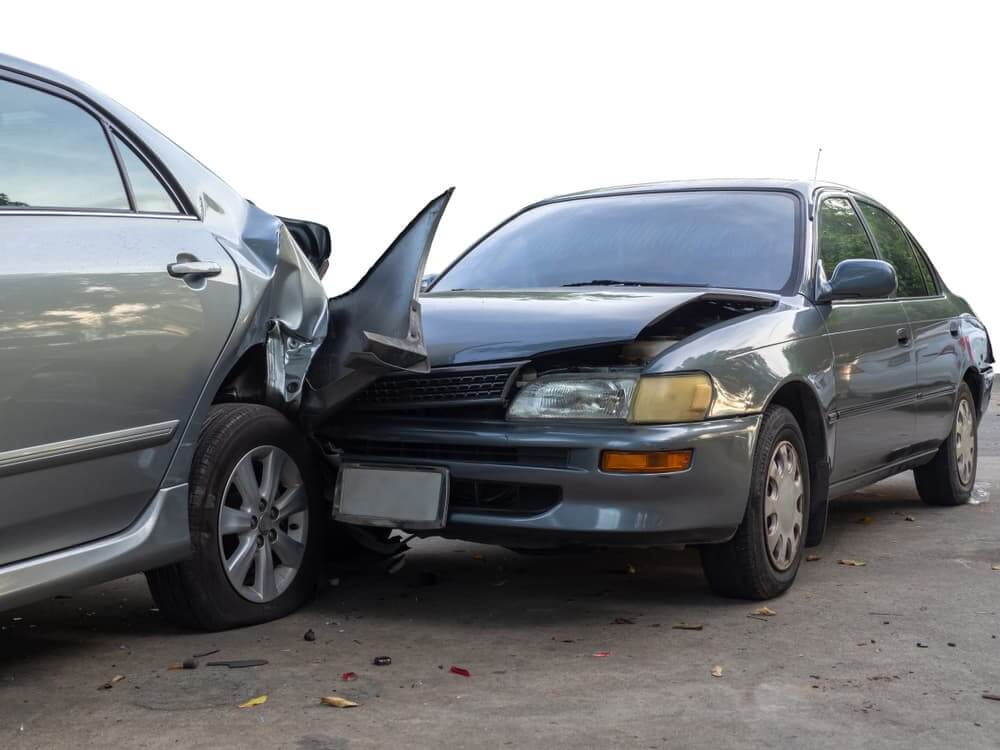 Car accident in Asheville between two grey sedan vehicles, one with hood crumpled against the smashed rear of another vehicle.
