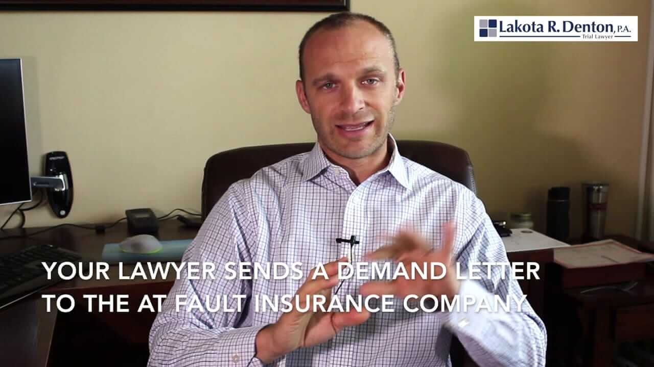 Lakota Denton sitting Asheville office wearing check white shirt with "Your Lawyer Sends a Demand Letter to the At Fault Insurance Company" text overlay