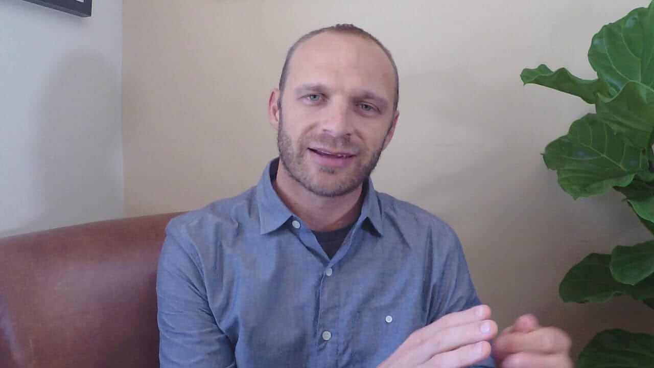 Accident lawyer Lakota Denton wearing blue shirt sitting on red brick couch in Asheville office.