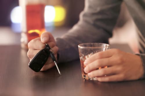 Focus on hands on a person holding a glass in one hand and car keys in the other hand
