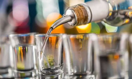 Liquid being poured into short glasses at a bar